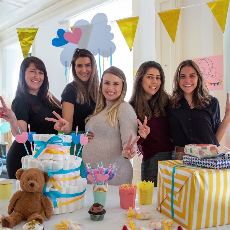Mother-to-be and friends smiling behind the shower table