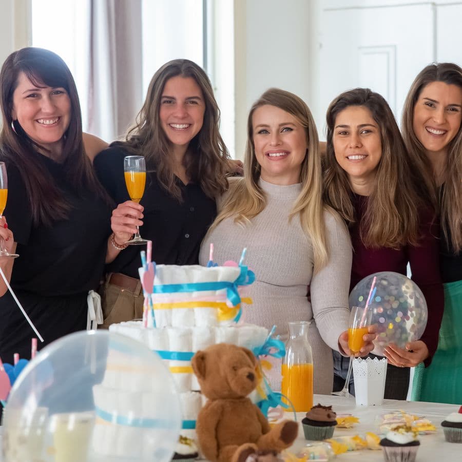 Group of women smiling together behind a diaper cake