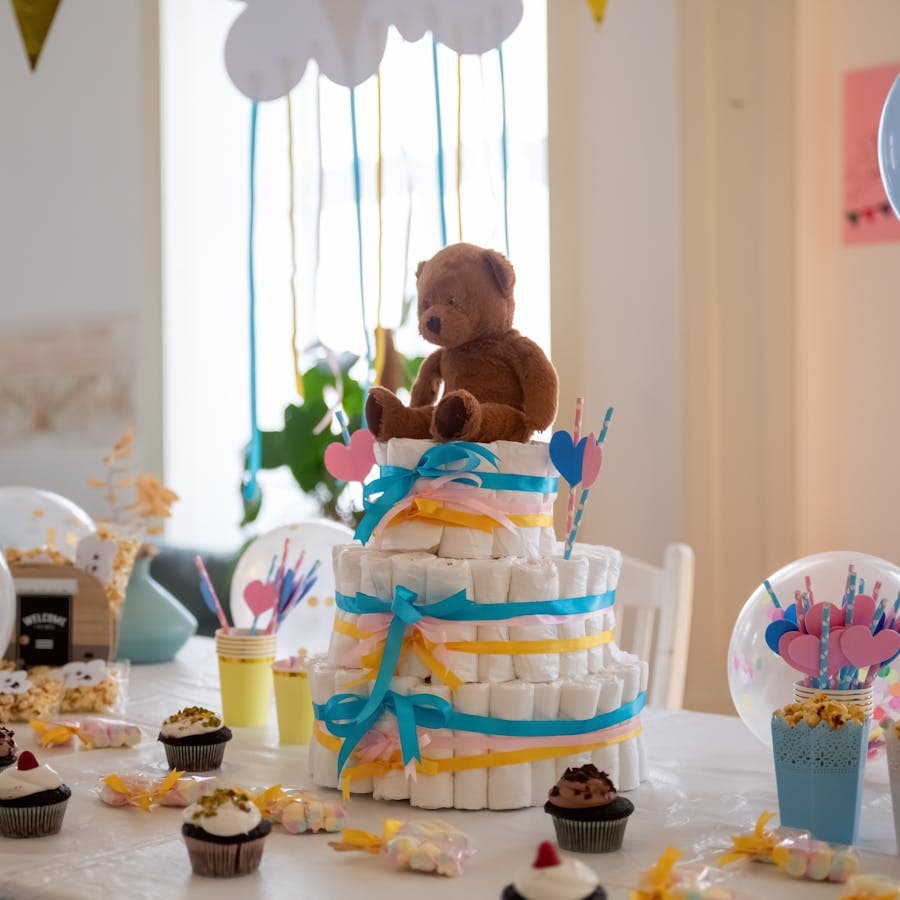 Baby shower table with a diaper cake, teddy bear, and cupcakes