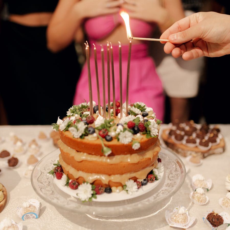Flower-topped birthday cake with tall candles on a dessert table