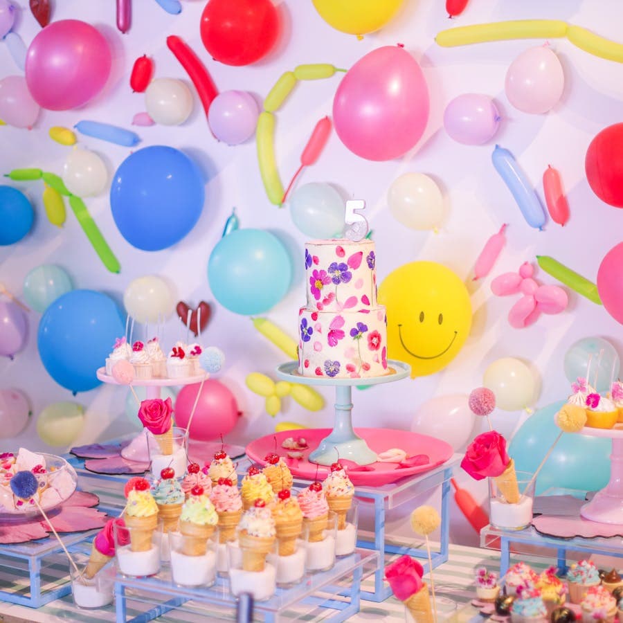 Colorful birthday dessert table with balloons and treats