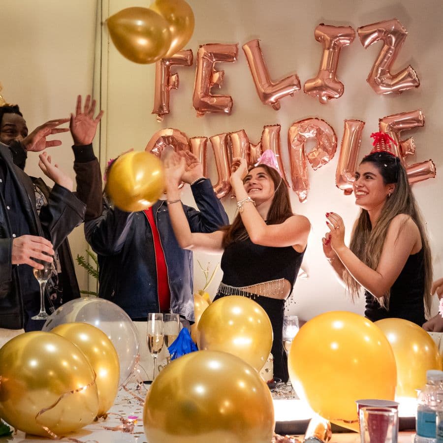 Friends celebrating with gold balloons and a birthday banner
