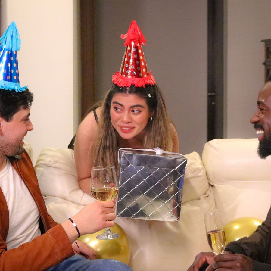 Friends laughing together on a couch at a birthday party