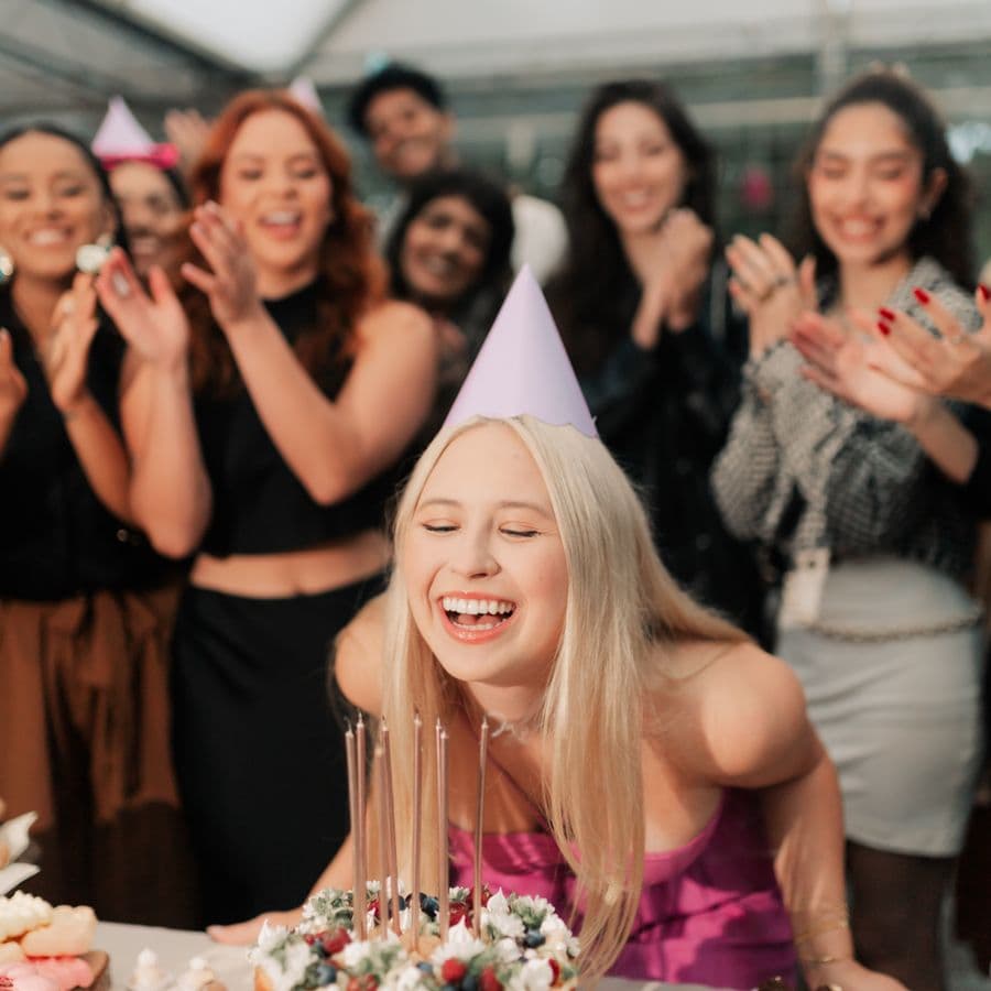 Birthday guest laughing as friends clap and cheer behind her