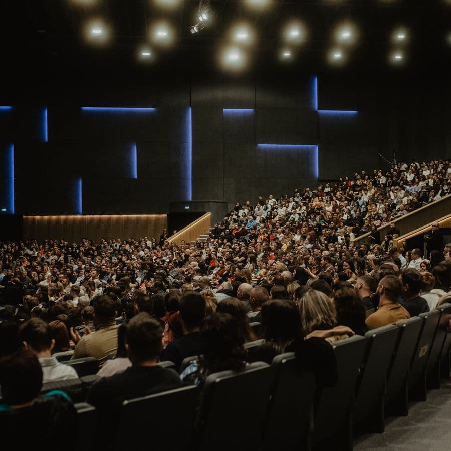 Packed auditorium audience watching a conference speaker