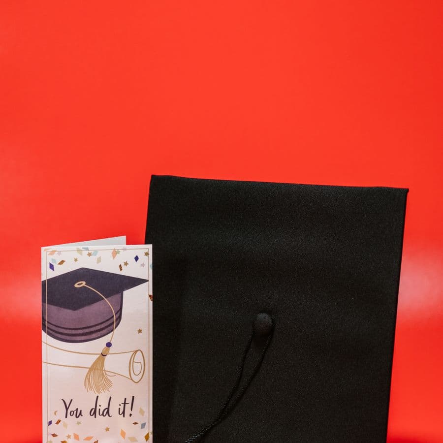 Graduation cap beside a You Did It card on red