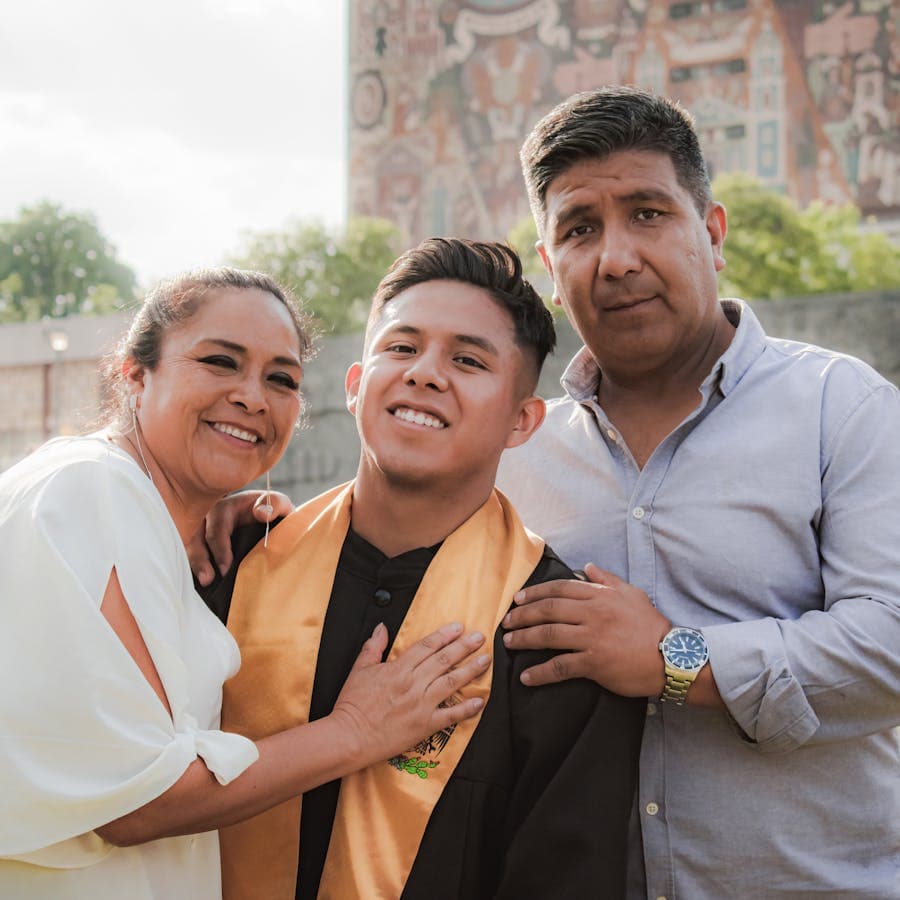 Proud parents embracing their graduate son outdoors