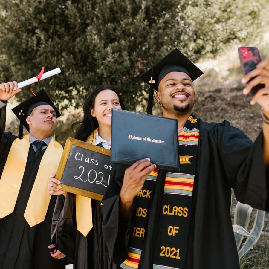 Friends in caps and gowns taking a graduation selfie