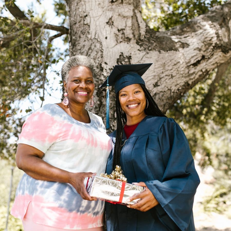 Mother handing a wrapped gift to her graduate daughter