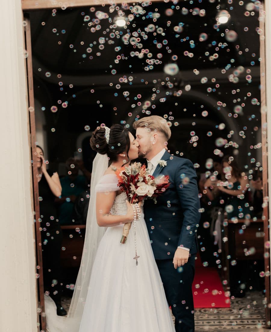 Newlyweds sharing their first kiss as guests blow bubbles around them