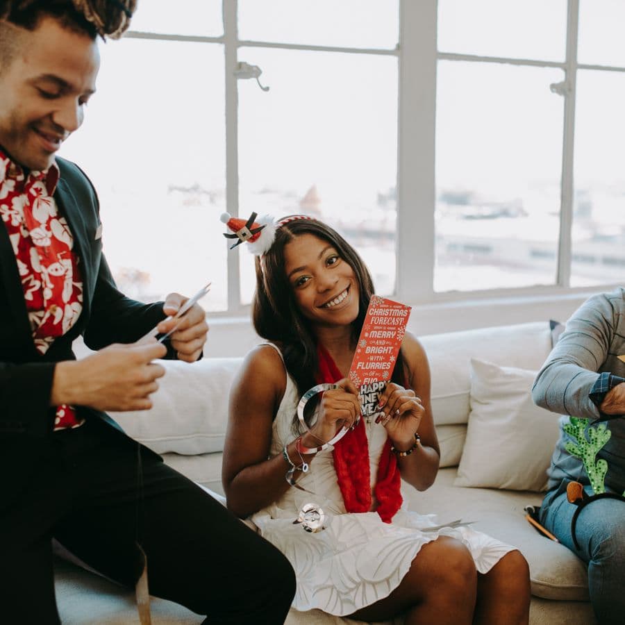 Friends laughing together on a couch with holiday props