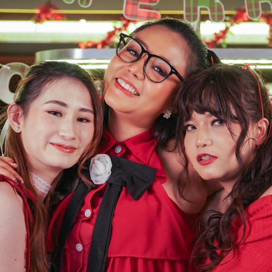 Three women in red posing together at a holiday party