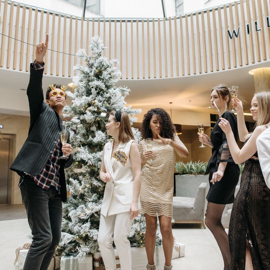 Guests celebrating near a decorated Christmas tree with champagne