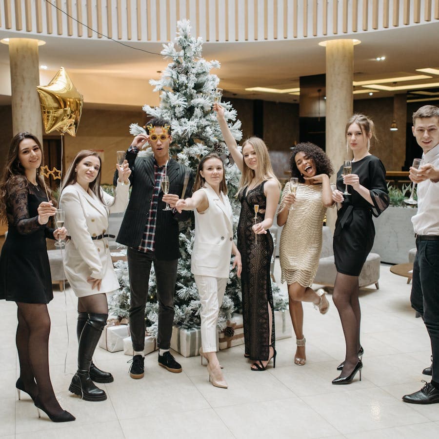 Group of friends raising champagne glasses near a holiday tree
