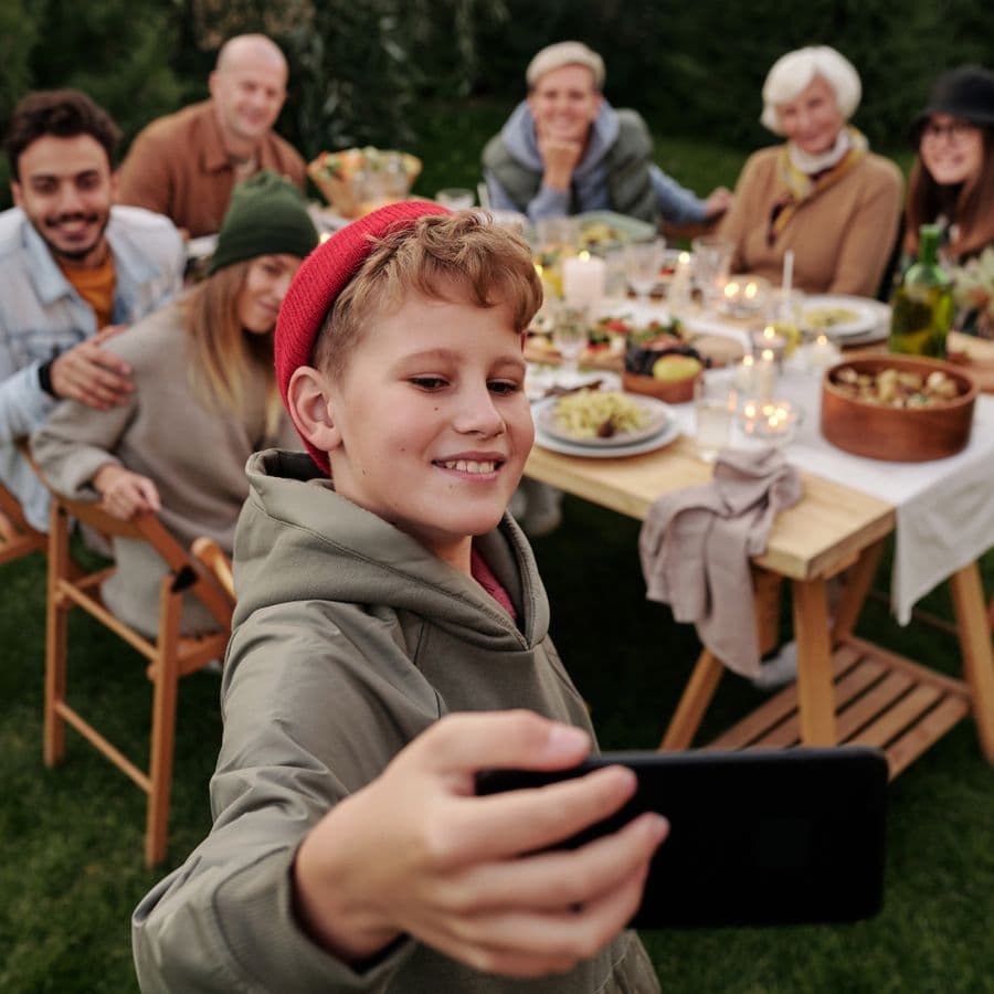 Boy taking a selfie with family at an outdoor dinner