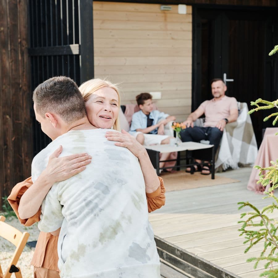 A warm welcome hug as family relaxes behind