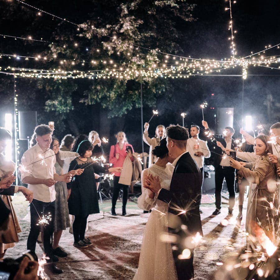 Couple dancing under twinkling lights surrounded by sparklers